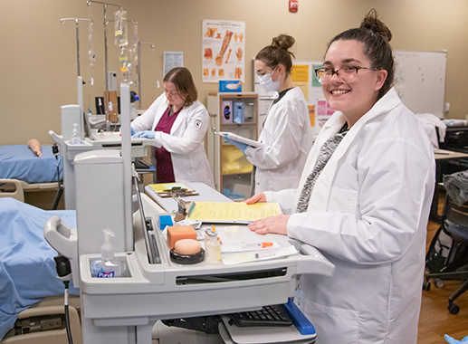 Female student in the Nursing lab classroom smiling at the camera